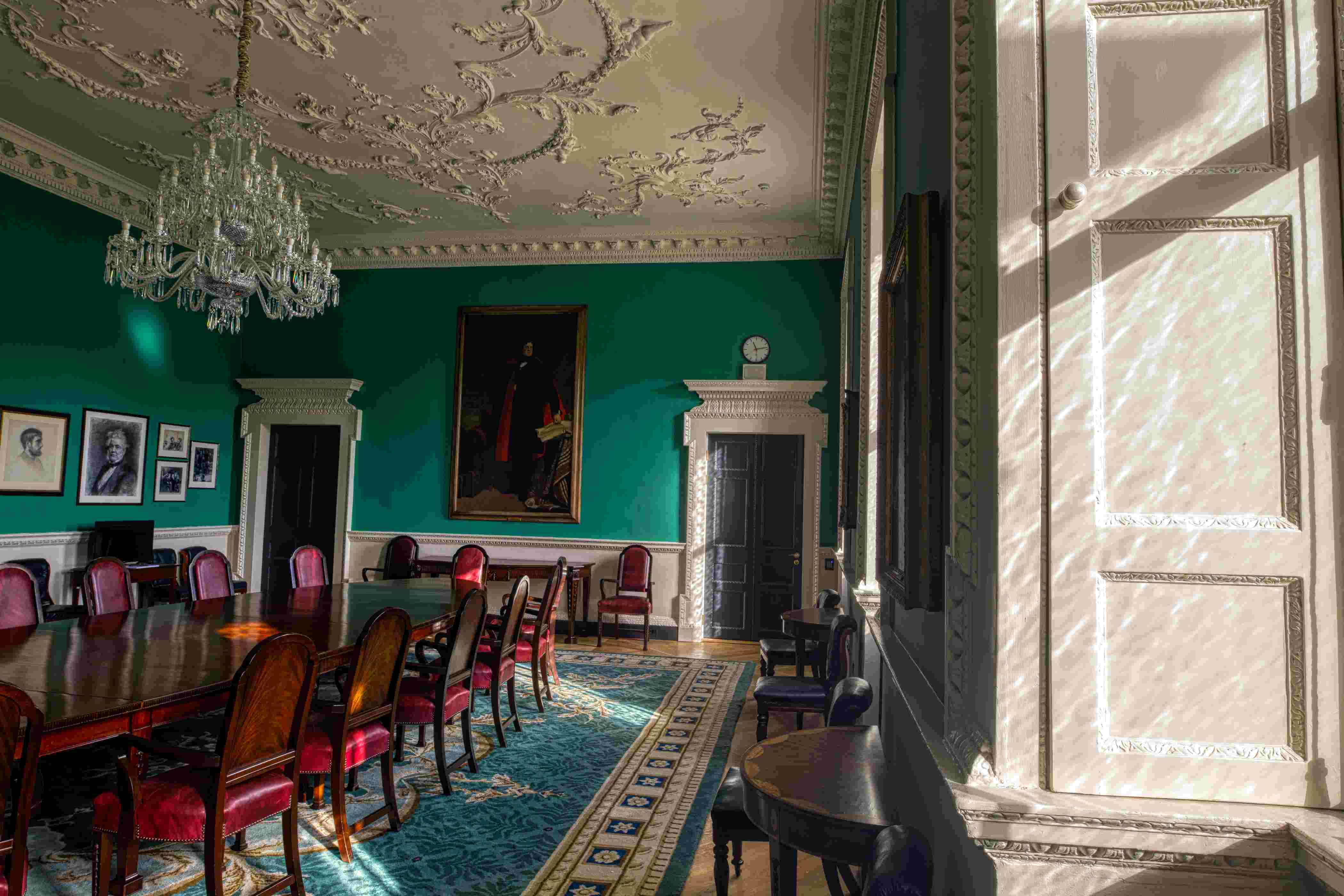 Interior of a room in Leinster House with sun shining in through a window. The room is furnished with a long table and chairs.