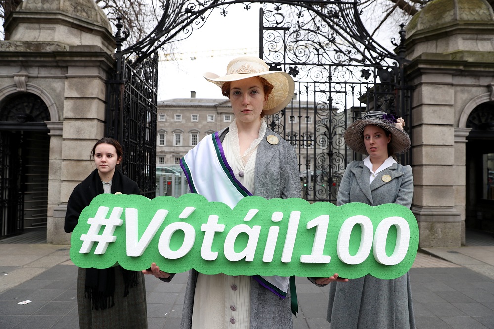 "Suffragettes" outside Leinster House displaying the Vótáil100 hashtag